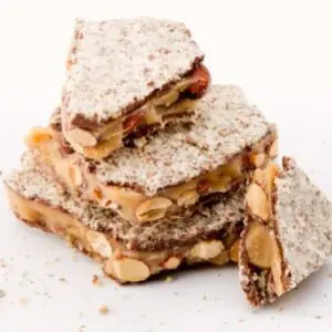 A stack of four pieces of food with nuts.